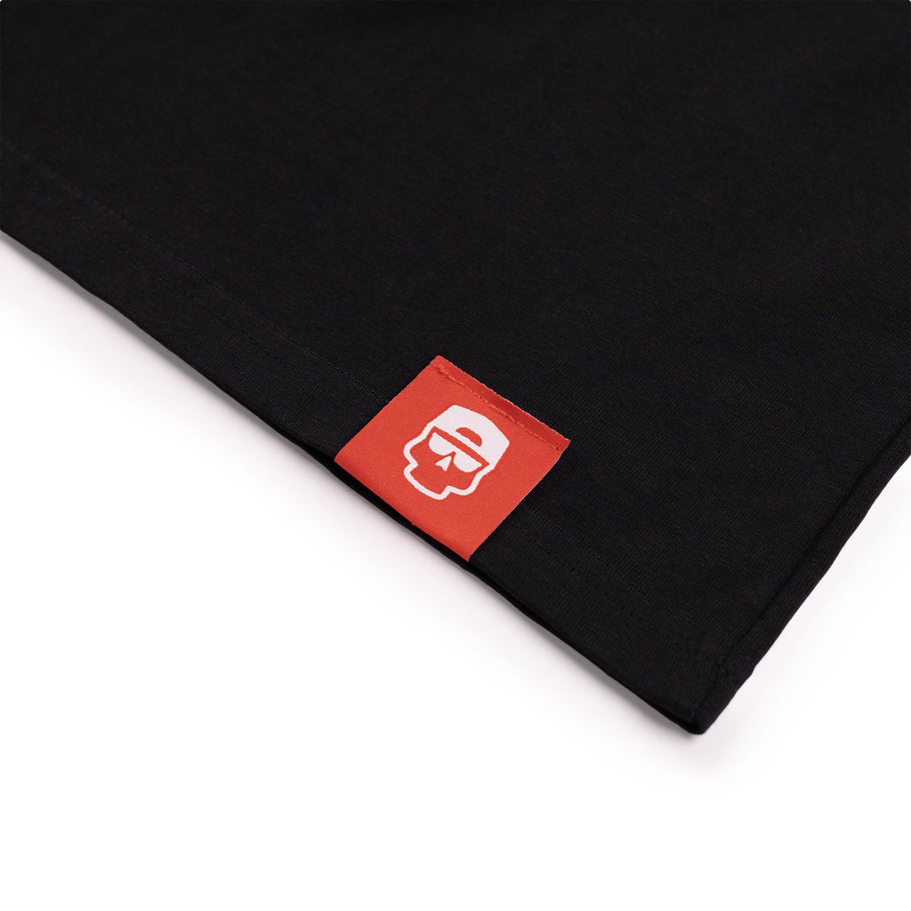 Red cotton tag on the hem of a black cotton t-shirt.